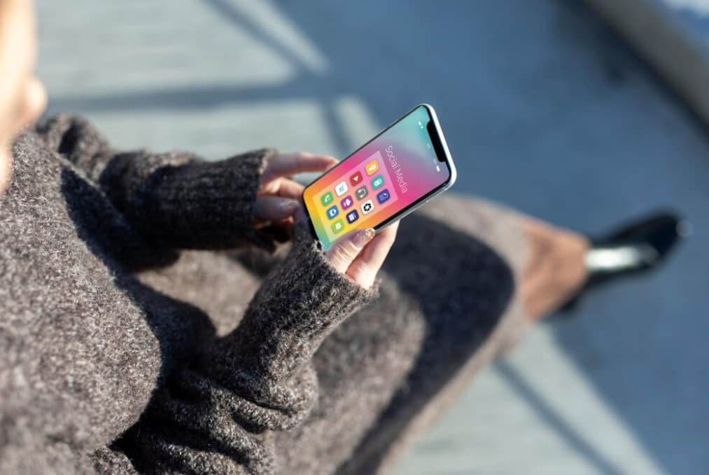 Person holding a smartphone with colorful app icons on screen